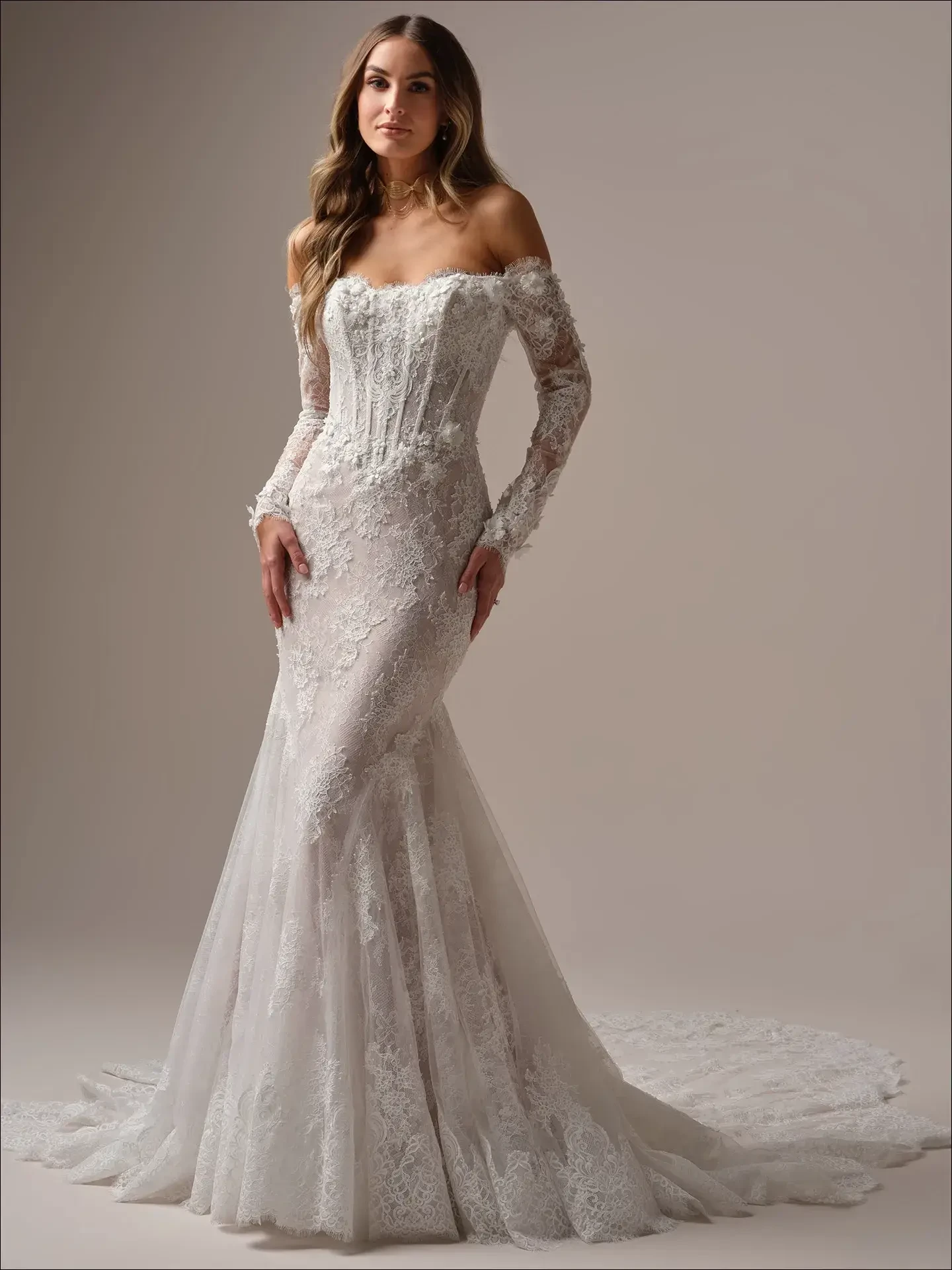 A woman in a long, off-shoulder lace wedding dress with a fitted bodice and flowing train. The elegant, intricate design conveys a sense of romance.