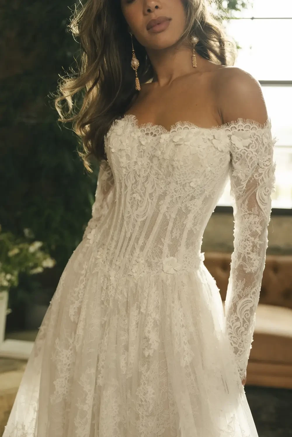 model is wearing an off the shoulder lace bridal gown