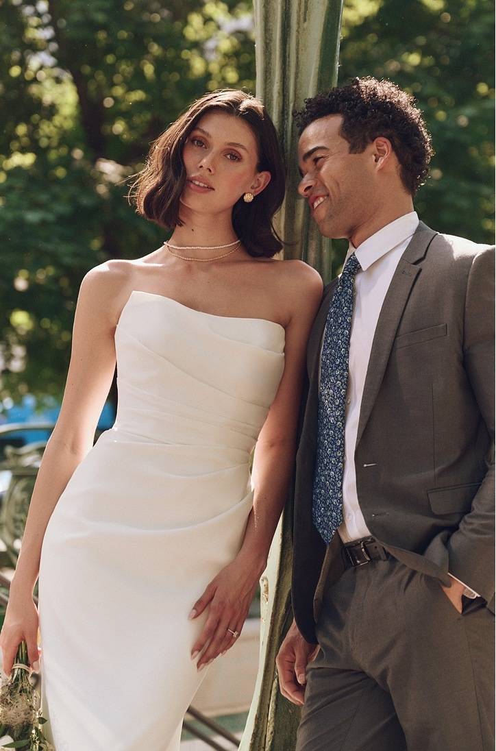 Model wearing a white bridal gown and posing near the men