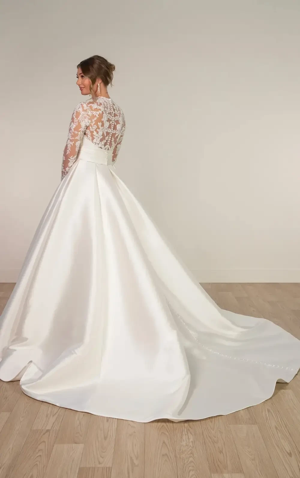 model is wearing a ball gown wedding dress with long lace sleeves and a high neckline