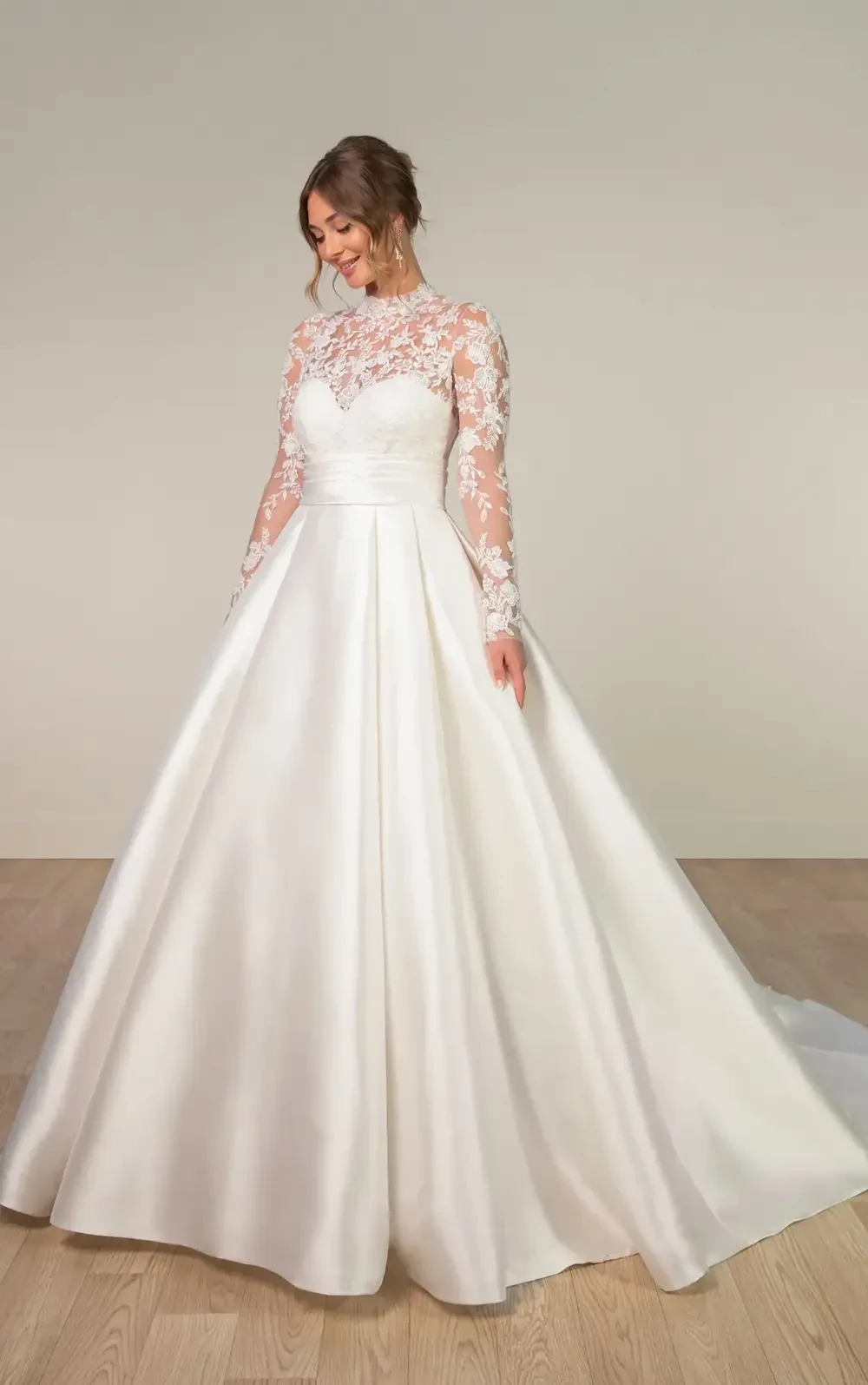 model is wearing a ball gown wedding dress with long lace sleeves and a high neckline